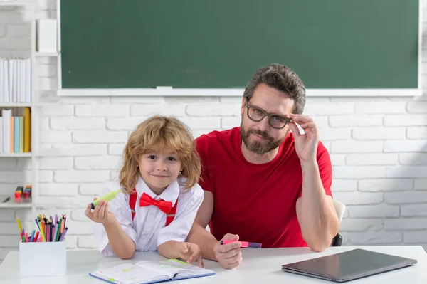 老师在课堂上帮助小学生 教育和学习概念 爸爸和儿子在学校做作业 — 图库照片
