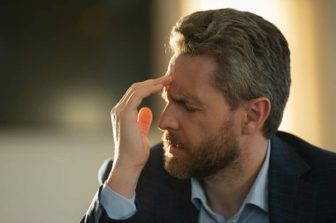 Yorgun adamın korkunç bir baş ağrısı var. Bitkin, sağlıksız hisseden, baş ağrısı hastalığına üzülen bir adam. Stresli orta yaşlı bir adamın baş ağrısı olan portresi. Migren ve baş ağrısı konsepti