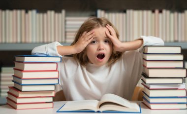 Kitap yığınları olan bir okul çocuğu. Okuluna geri dön. Çocuk eğitimi ve okul konsepti. Kütüphanede kitap okuyan öğrenci portresi. Çocuk gelişimi, okumayı öğren.