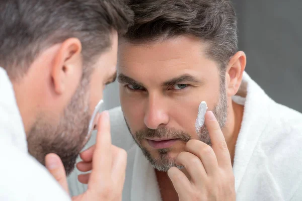顔にクリームをかけた男 完璧な柔らかい肌のチャーミングな男 男性の美しさとスキンケアの概念 男性化粧品皮膚治療 朝の衛生状態 男性化粧品と健康 スキンケア — ストック写真