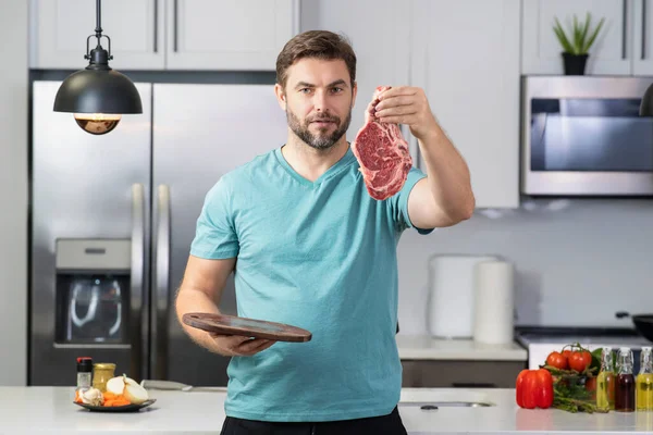 穿着厨师制服的千禧年恐慌人在厨房里拿着肉牛肉 餐馆菜单上有肉 宣传肉类概念 — 图库照片