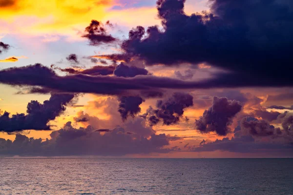Clouds over the sea, sunrise. Sea wave. Colorful beach sunrise with calm waves. Nature sea sky. Sunrise with clouds of different colors against the blue sky and sea