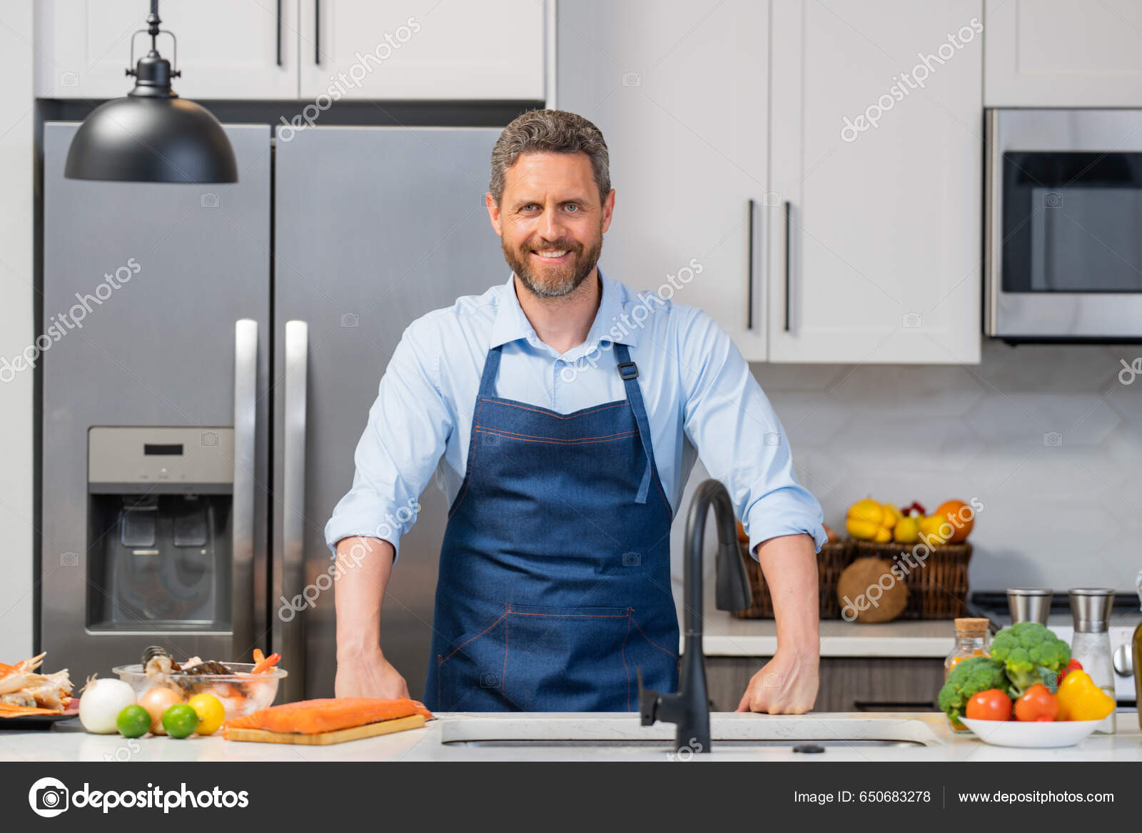 Chef en cocinar delantal de cocina en la cocina. Hombre en la cocina con  verduras. Retrato de hombre casual que cocina en la cocina con ingredientes  vegetales. Chico Fotografía de stock 