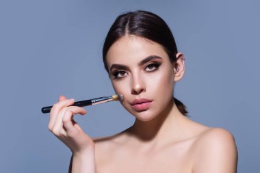 Woman applying foundation powder or blush with makeup brush. Facial treatment, perfect skin, natural make up, facial beauty. Isolated on studio background. Applying makeup