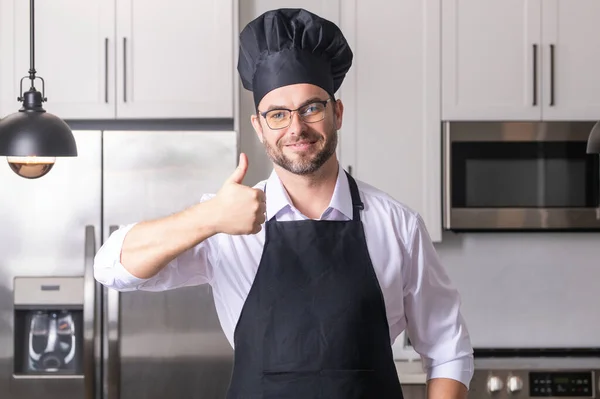 親指を立てて幸せなパン屋 キッチンのシェフキャップにシェフの男の肖像画 エプロンとシェフの制服を着た男とシェフの帽子 キャラクターキッチン 広告のためのシェフ — ストック写真