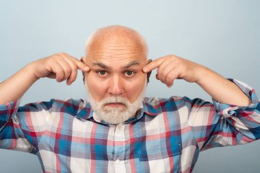 Stüdyoda izole edilmiş komik orta yaşlı bir adam. Gri saçlı, olgun, son sınıf öğrencisinin yakın portresi.