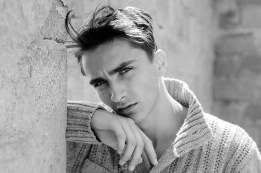 Gri duvara karşı tatmin olmuş genç bir adamın portresi. Gri arkaplandaki modaya uygun Latin adamın yüzünü kapat