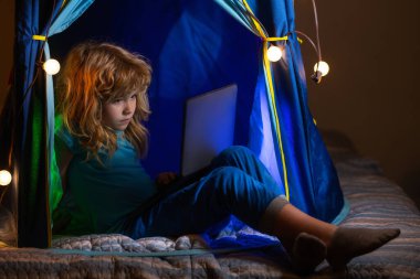 Sevimli anaokulu çocuğu yatakta uyumadan önce dizüstü bilgisayarla çizgi film izliyor. Aletlerin aşırı kullanımı ve bağımlılığı. Küçük hacker, genç programcı