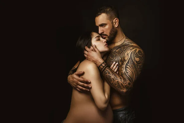 Couple in love pregnant cuddling, waiting for baby. Real romantic passionate moment. Bearded man with tattoo clasping beautiful girlfriend. Emotive of sexy couple