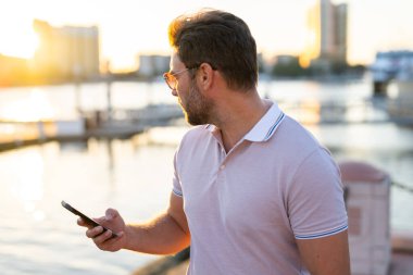 Büyük şehirde telefonda konuşan yakışıklı bir adamın portresi. Sokakta telefonla konuşan, günlük kıyafetli seksi bir adam. Şehir yaşam tarzında başarılı bir erkek model. İş telefonu görüşmesi