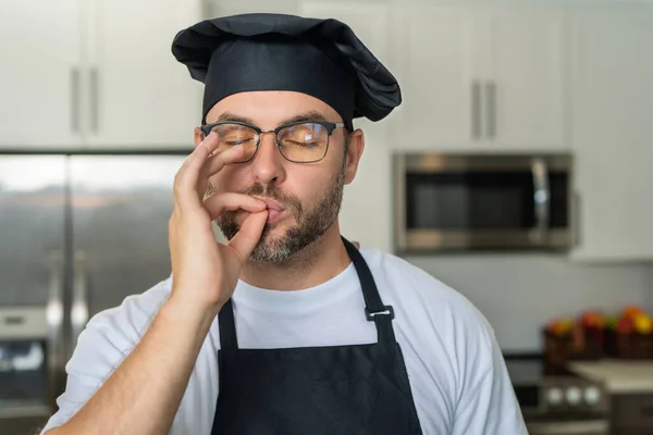 Man chef cooker, baker. Male chefs with sign of perfect food. Chef man cooking, showing sign for delicious. Chef, cook making tasty delicious gesture by kissing fingers. Chefs cook in hat and apron