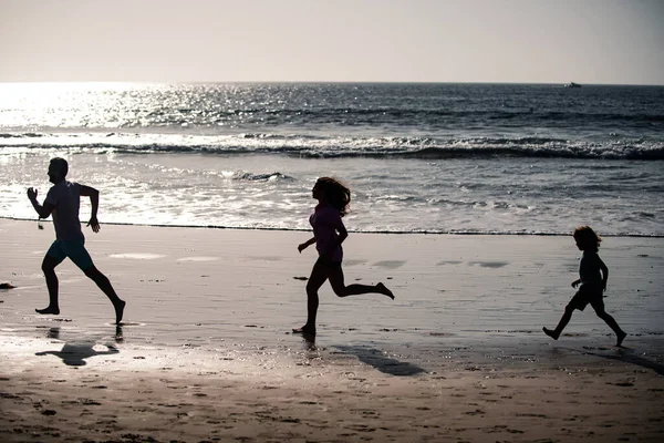幸せな若い家族はビーチランで楽しみ 日没でジャンプします 子供と熱帯夏休みに積極的な親や人々の屋外活動 — ストック写真