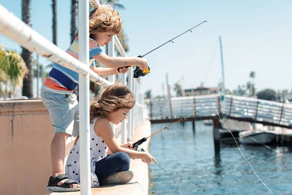 Couple of kids fishing on pier. Child at jetty with rod. Boy and girl with fish-rod