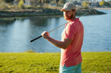 Golfçü akşam golf sahasında golf oynuyor. Güneşin altında golf oynayan bir adam.