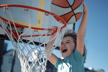 Basketbol maçında smaç yapan çocuk basketbolcunun yakın çekimi. Çocuk sporcu, basketbol sahasında açık havada..