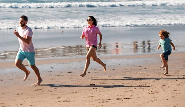 スポーティ家族の父 母と赤ちゃんの息子のジョギング 黒砂のビーチで海の波に沿ってウォータープールで実行されます 夏休みに子供と一緒に旅行ライフスタイル バナー コピースペース — ストック写真