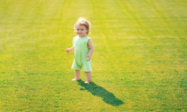 赤ん坊は緑の芝生の上で裸足で立っている 夏の公園で遊んでいる男の子 幸せな子供時代と子供の医療 — ストック写真
