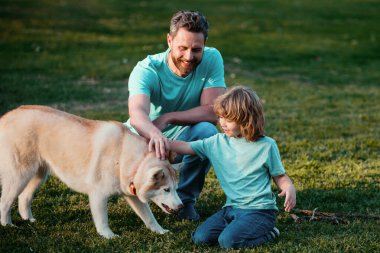 Baba oğul bahar parkında köpekle oynuyorlar. Evcil hayvanla dost aile kavramı