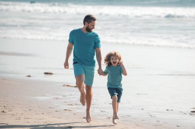 Baba ve oğul denizde koşuyor. Arkadaş canlısı aile kavramı ve yaz tatili