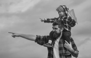 Baba ve oğul birlikte oynuyorlar. Babasıyla dışarıda oynayan sevimli çocuk. Çocukluk. Baba ve oğul. Mutlu çocuk kağıt uçakla oynuyor. Kaygısız