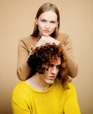 Birbirine aşık çiftler, birbirine sarılıp kucaklaşan şehvetli aşıklar. Genç bir çiftin portresi. Stüdyoda bej arka planda moda bir çift. Modaya uygun bir çift.