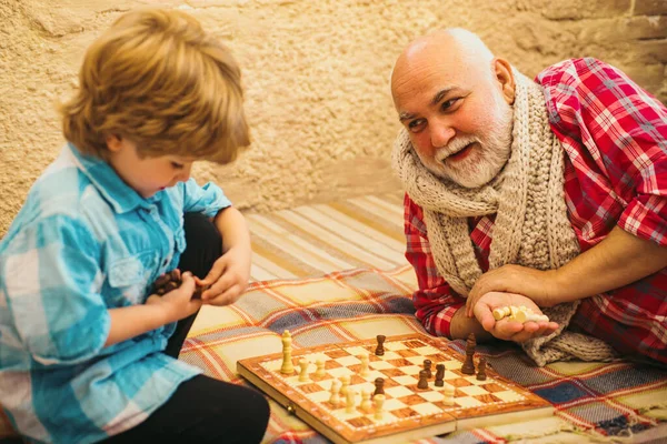 stock image Childhood. Senior man teaching his grandson to play chess. Kid Playing Chess. Grandfather and grandson concept