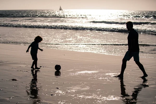 父と息子はビーチでサッカーやサッカーをする — ストック写真
