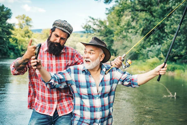 快乐兴奋的男人朋友 一个快乐的老人钓鱼的画像 祖父和儿子是渔夫 年轻人和老人在河里或湖中钓菠萝 — 图库照片