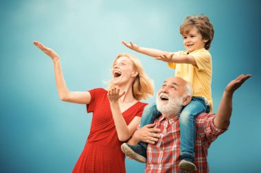 Mutlu çocuk oyuncak kanatlarla oynuyor yaz gökyüzü arka planına karşı. Mutlu büyükbabanın portresi. Torununu sırtında taşıyor ve yukarı bakıyor.