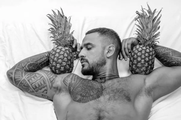 Svalnatý Muž Drží Bicepsech Ananas Brutální Sportovec Odpočívá Posteli Steroidy — Stock fotografie