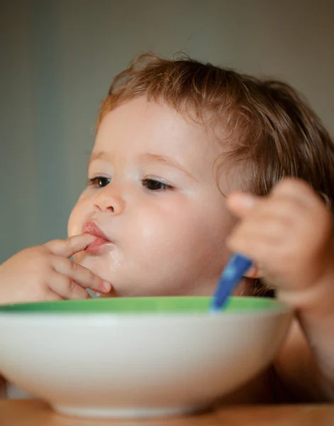 皿から指で食べるキッチンで面白い小さな赤ちゃん おいしい指を舐める — ストック写真