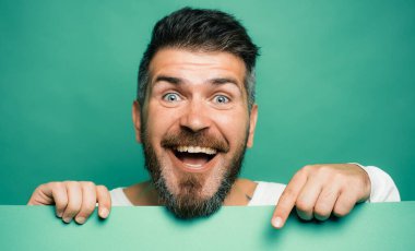 Sakallı adam yeşil masayı işaret ediyor. Mart ayında gelenekler ve kutlamalar. Aziz Patrick Günü 'nün yeşil rengi. Heyecanlı, tutkulu bir adam yüzü. Boşluğu kopyala