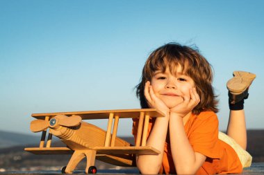 Komik çocuk ya da çocuk pilot oyuncak uçakla oynuyor, başlangıç özgürlüğü ve tasasız. Uçma hayalleri. Çocuk gökyüzüne karşı oyuncak uçakla oynuyor. Çocuklarla yaz tatili