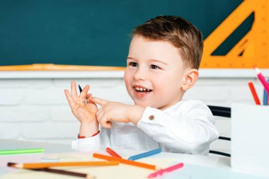 Gülümseyen mutlu çocuk ilk kez okula gidiyor. Neşeli gülümseyen küçük çocuk tahtaya karşı eğleniyor. Okula Dönüş