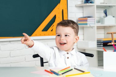 Karatahta arka planında eğlenen komik küçük çocuk. Okul kavramı
