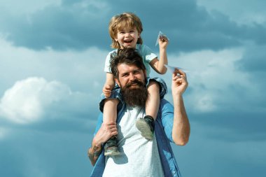 Nesil. Baba oğlunu parka geri götürüyor. Baba ve oğul birlikte kağıt uçak yapıyorlar. Mutlu bir babanın portresi. Oğlunu sırtında taşıyor ve yukarı bakıyor.