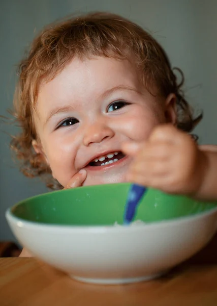 赤ん坊はスプーンを口に持っている 幸せな子供はスプーンで自分自身を食べる 食べ物を食べる子の起動 — ストック写真