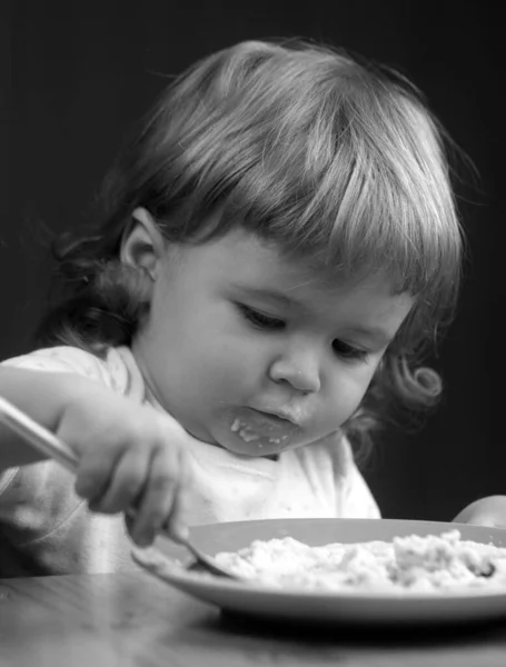 儿童饮食 营养概念 在家里厨房里用勺子和盘子把小宝宝的脸弄得漂亮 — 图库照片