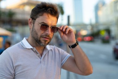 Dışarıdaki yakışıklı erkek modelin portresi. Polo giymiş şık bir adam. Moda erkeği sokakta poz veriyor. Şehir tarzı. Genç adam şehirde yürüyor. Yanında poz veren varlıklı iş adamı