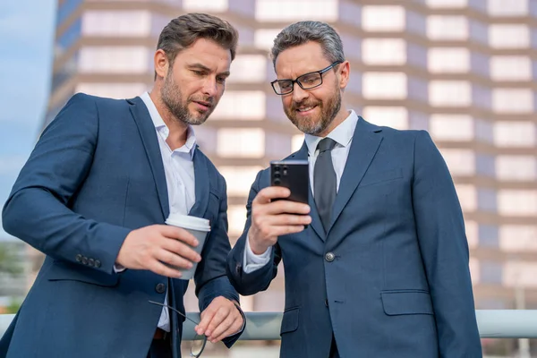 Två Affärsmän Använder Telefon Utomhus Bank För Två Affärsteam Män — Stockfoto
