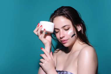 Skin care. Woman applying face cream, studio portrait. Beautiful model with moisturizing cream anti age cream on perfect soft skin. Beauty cosmetic product industry
