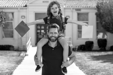 Baba oğlunu destekliyor ve motive ediyor. Çocuk ilkokula gidiyor. Sonbaharın ilk günü. Baba oğul okul bahçesinde eğleniyorlar. Arkadaş canlısı aile kavramı