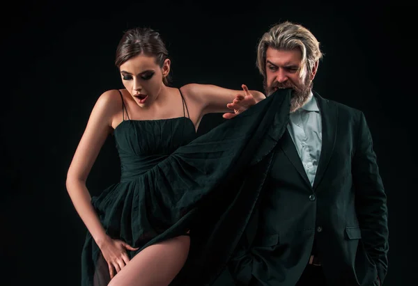 Sexy couple in elegant dresses tender passion. Black background. Seductive love