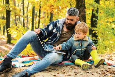 Ekoloji dersi. Orman okulu ve ekoloji eğitimi. Adam sakallı baba ve küçük oğlu ormanda dizüstü bilgisayar ile. Ekoloji nin yetiştirilmesi. Baba oğlumodern teknoloji kullanımı öğretir. Doğaile birleşmiş.