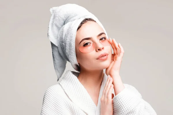 Portrait of beauty woman with eye patches showing an effect of perfect skin. Under eye masks for puffiness, wrinkles, dark circles. Sexy woman in white bathrobe applying eye patches