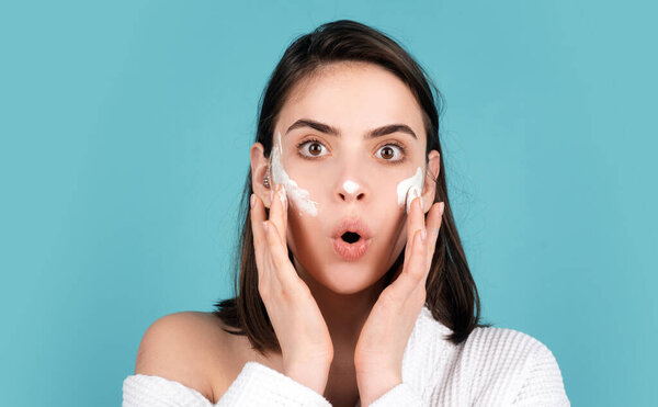 Beauty amazed woman with clean healthy skin, natural make up, spa concept. Beautiful excited girl apply a cleansing mask on face