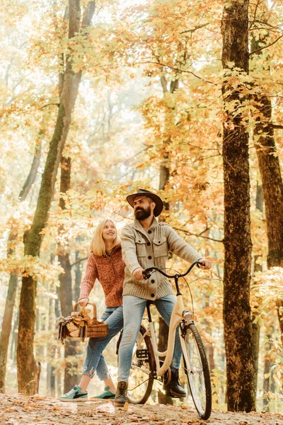 Couple in love ride bicycle together in forest park. Bearded man and woman relaxing in autumn forest. Romantic couple on date. Date and love. Autumn date hike in forest. Romantic date with bicycle.