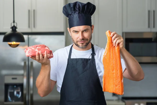 ヘルシーな料理を準備するシェフの台所の肖像画 魚と肉 サーモンと牛肉を調理する男 家のキッチンで新鮮な魚や肉 サーモンや牛肉を準備しているハンサムな男 — ストック写真