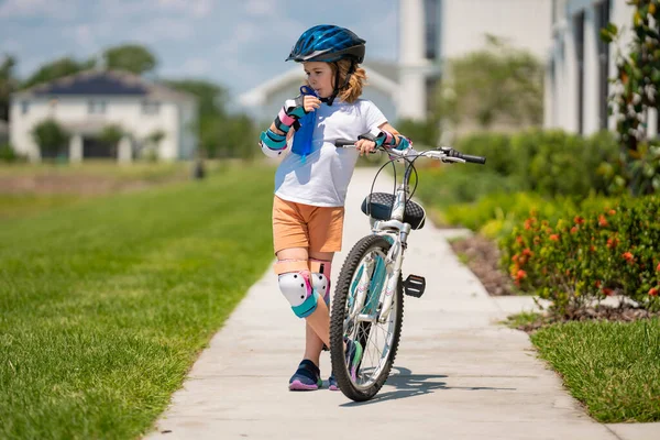 Kid riding bike in a helmet. Child with a childs bike and in protective helmet. Articles on safety and kid sports and activity. Happy kid boy having fun in summer park with a bicycle