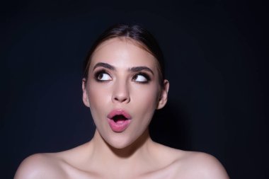 Siyah arka planda izole edilmiş güzel bir kadın portresi. Duygusal olarak şaşırmış kadın yüz ifadesi kavramı. İnsani duygular. Şok olmuş kadın elleriyle ağzını kapatıyor. Heyecanlı bir kadın model. Omg kavramı